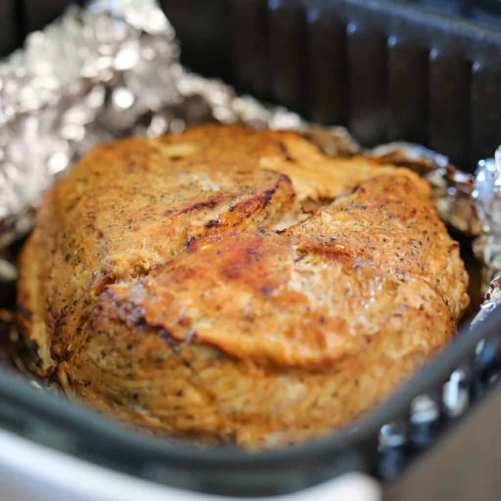 a 3 lb boneless skinless turkey breast air fryer roast in the basket after flipping halfway