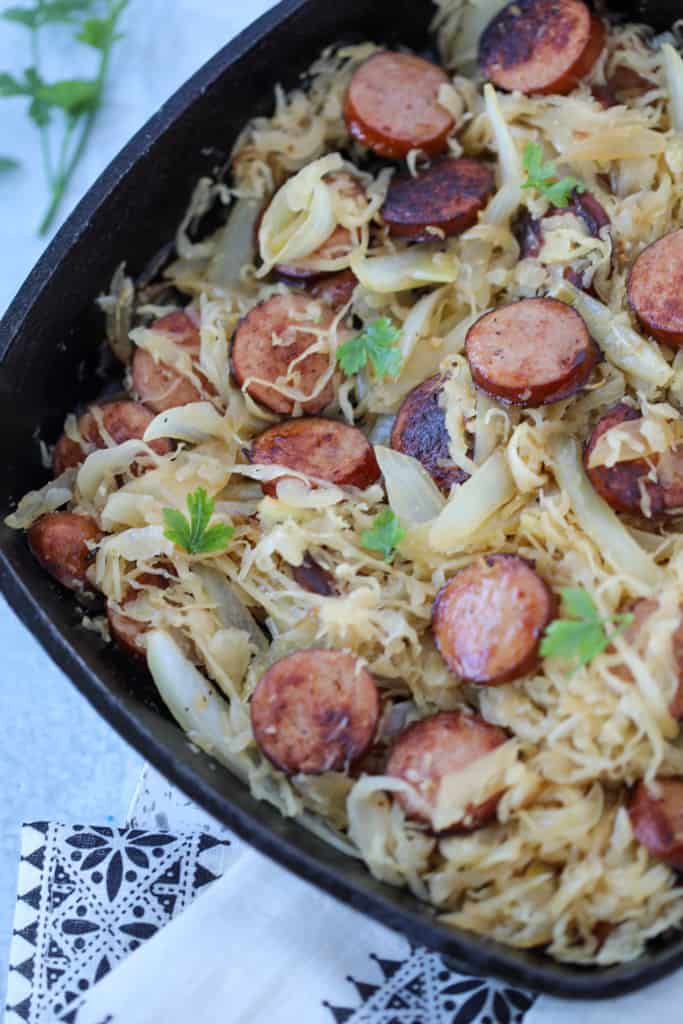 kielbasa and sauerkraut on the stove in a cast iron skillet