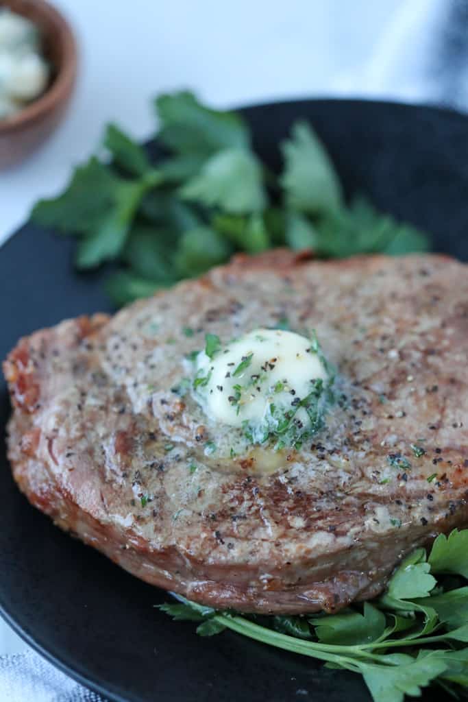 ribeye steak in air fryer on a plate with butter