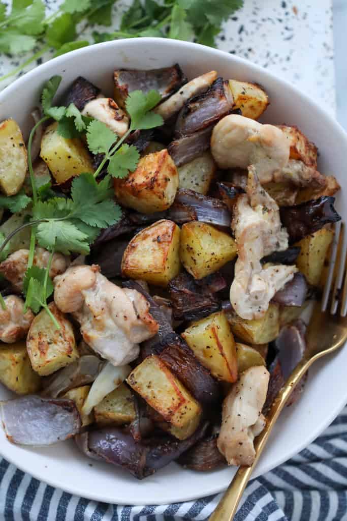 air fryer chicken thighs and potatoes after cooking in a white bowl