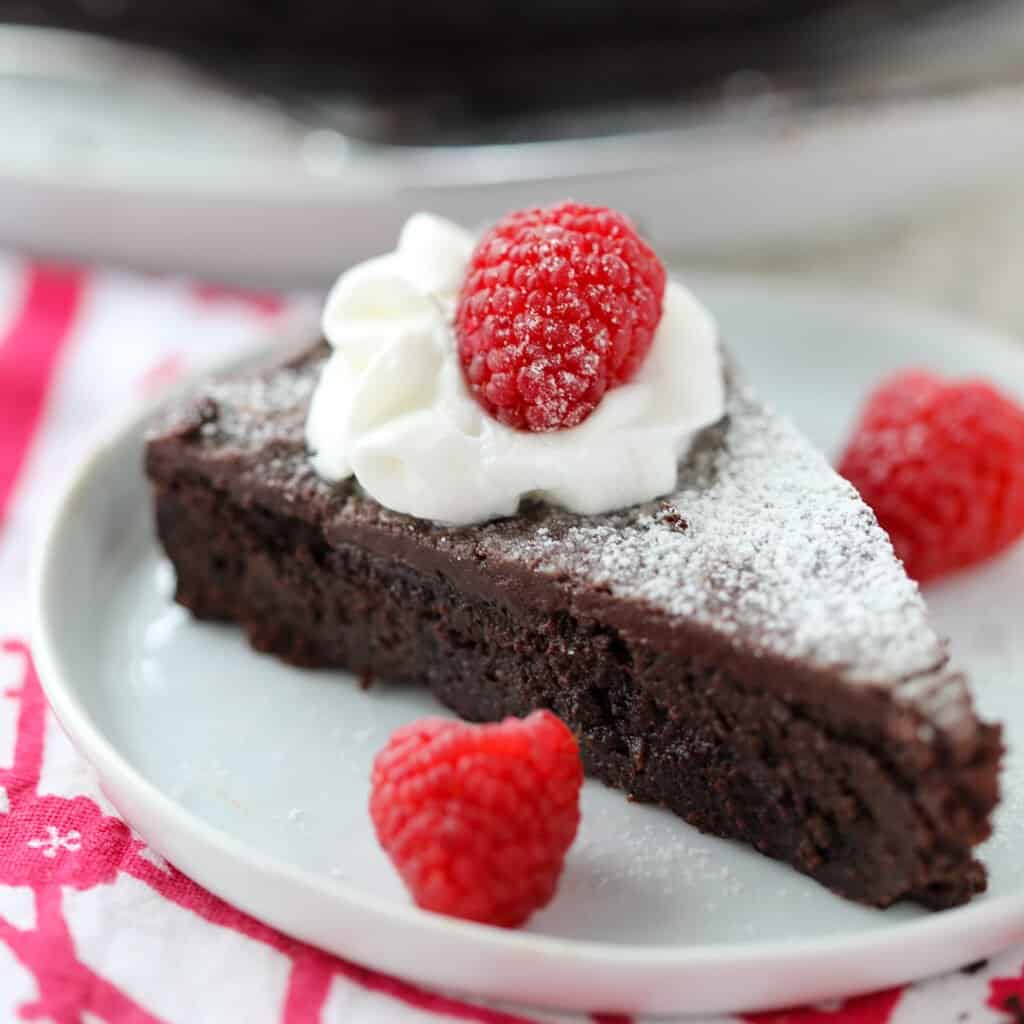 flourless chocolate cake with ganache slice on a white plate