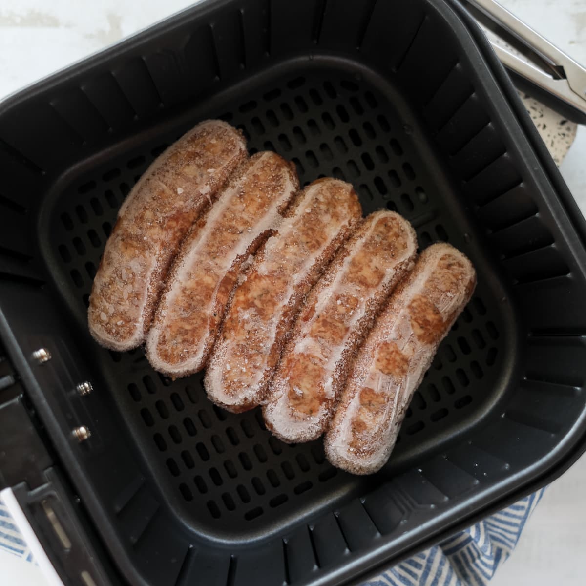 frozen sausage in air fryer in a block inside the air fryer basket