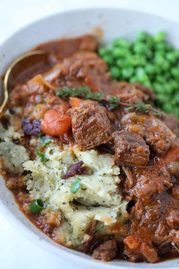 instant pot guinness beef stew in a white bowl with mashed potatoes