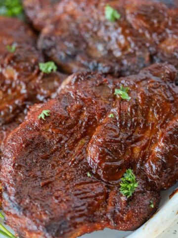 oven pork steaks with barbecue sauce on a platter with garnish before eating