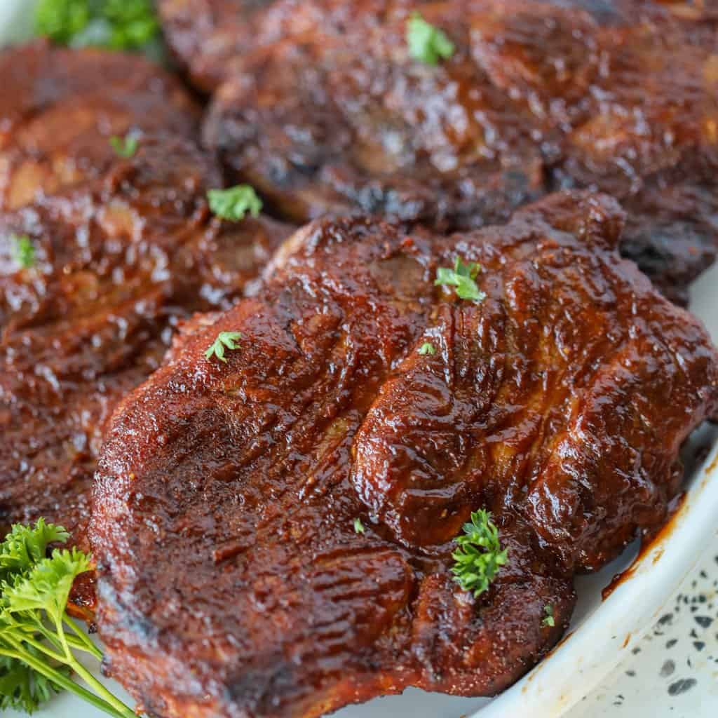 oven pork steaks with barbecue sauce on a platter with garnish before eating