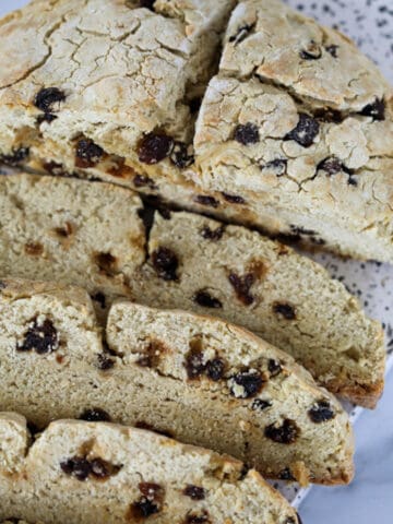 gf irish soda bread partially sliced with raisins on a white cutting board