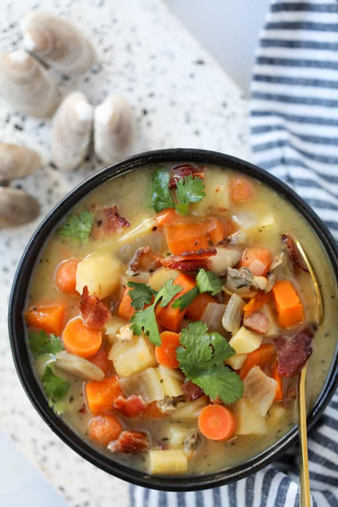 dairy free clam chowder in a black bowl garnished with bacon