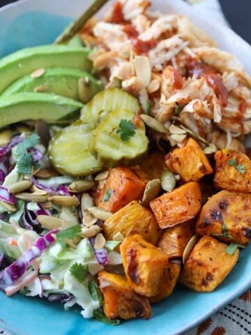 bbq chicken bowls with sweet potatoes and garnishes like bbq sauce and cilantro