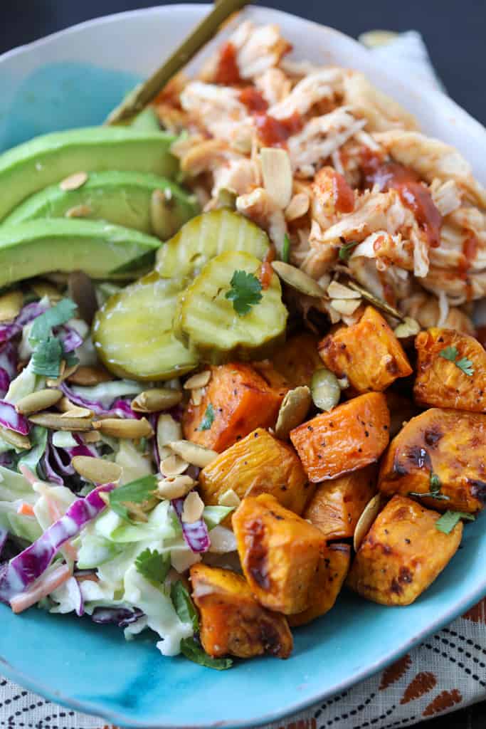 bbq chicken bowls with sweet potatoes and garnishes like bbq sauce and cilantro
