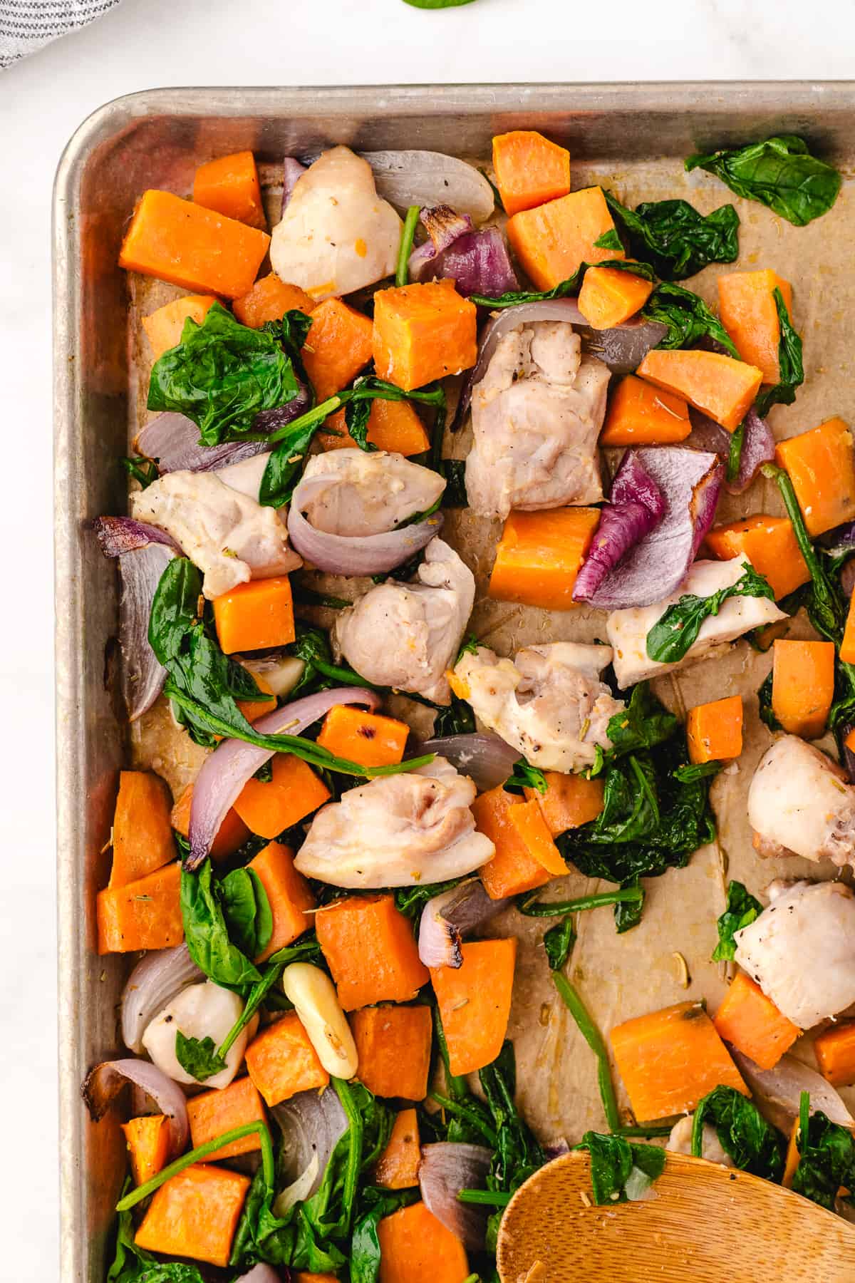 chicken thighs and sweet potatoes close up on a sheet pan