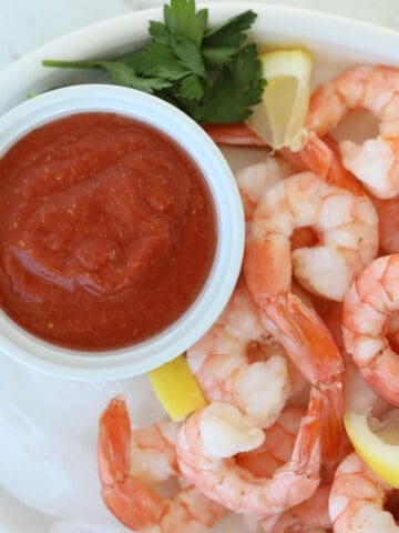 low carb cocktail sauce on a white plate with cooked shrimp