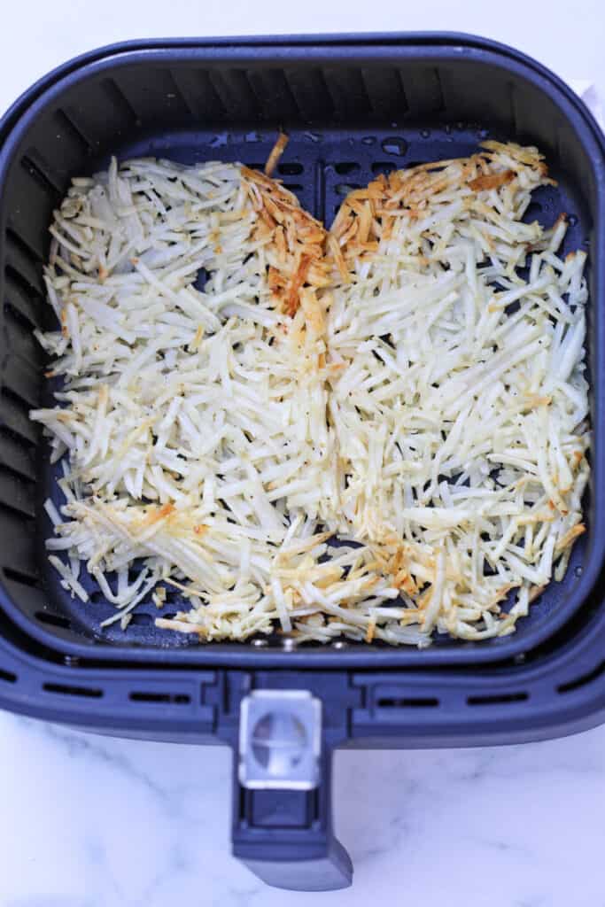 air fryer frozen hash brown shredded after cooking in the air fryer basket