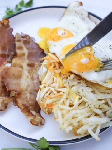 air fryer shredded hash browns on a plate with bacon and eggs