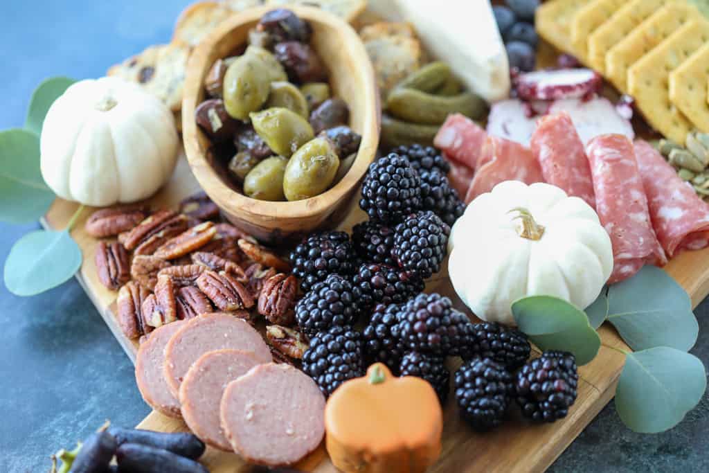 2 autumn charcuterie board berries, nuts, cheese and meats arranged together