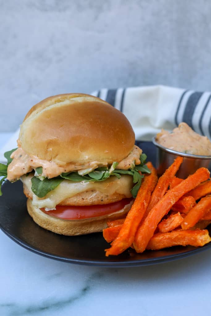 air fryer frozen salmon burgers on a plate with fries and old bay sauce