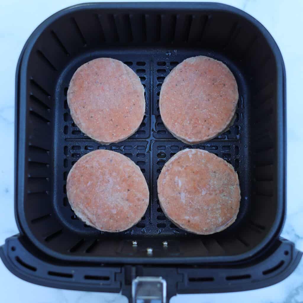 air fryer frozen salmon patties getting put in an air fryer basket