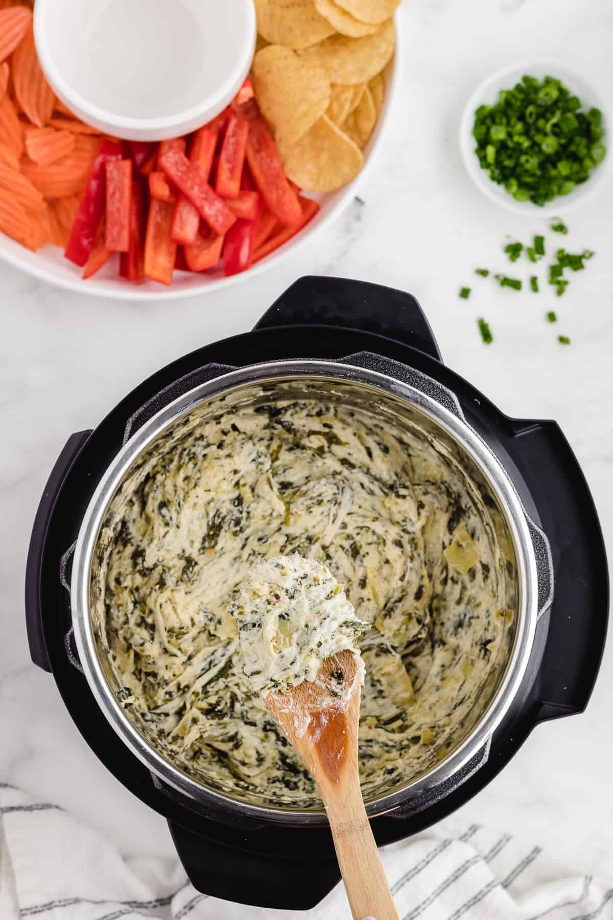 hot spinach dip on a spoon pulling it out of the pressure cooker