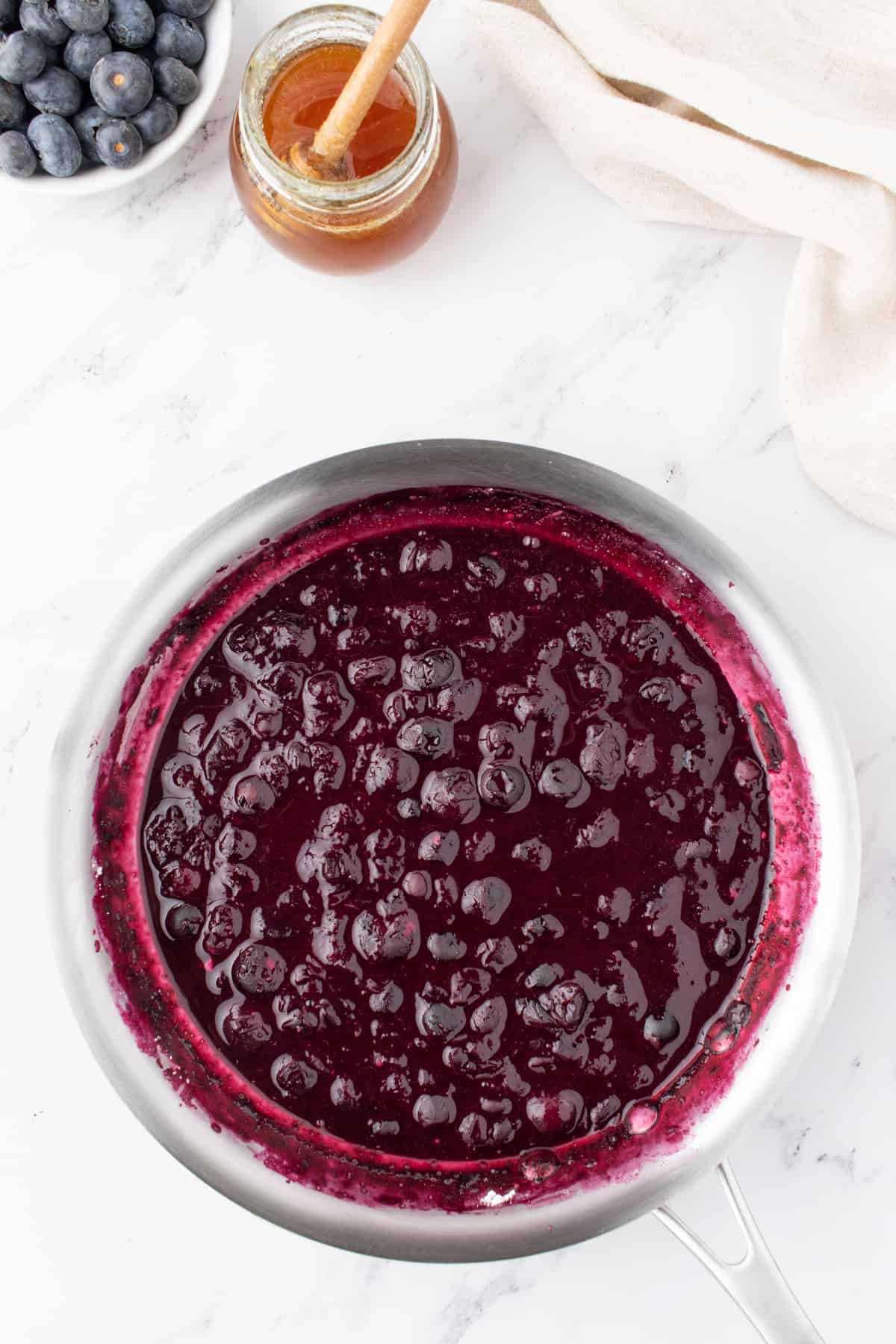 making a blueberry sauce in a saucepan for topping chia seed puddings