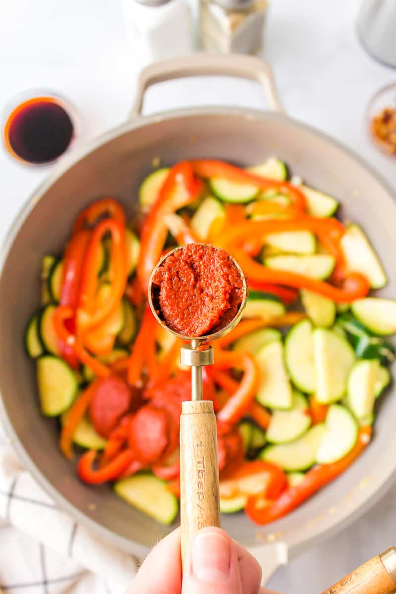 adding red curry sauce to the vegetables