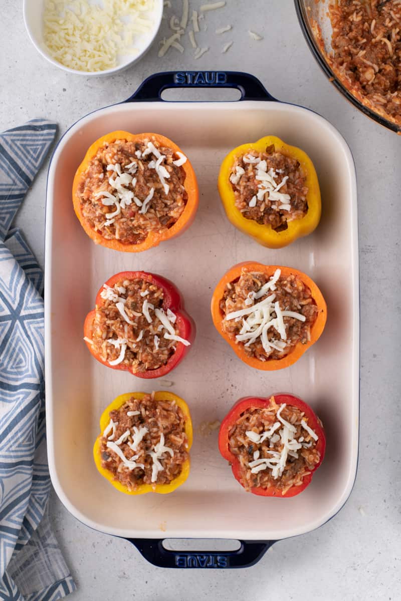 stuffing the bell peppers and topping them with cheese before baking