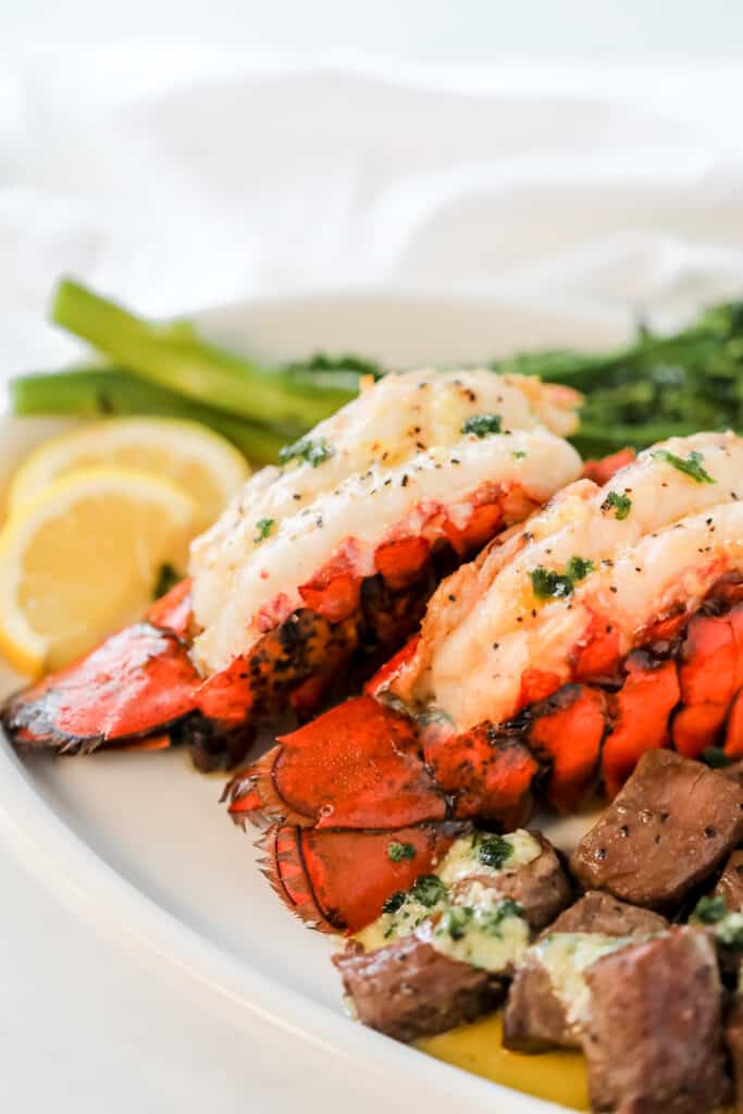 butterflying a lobster tail served on a white plate with broccoli
