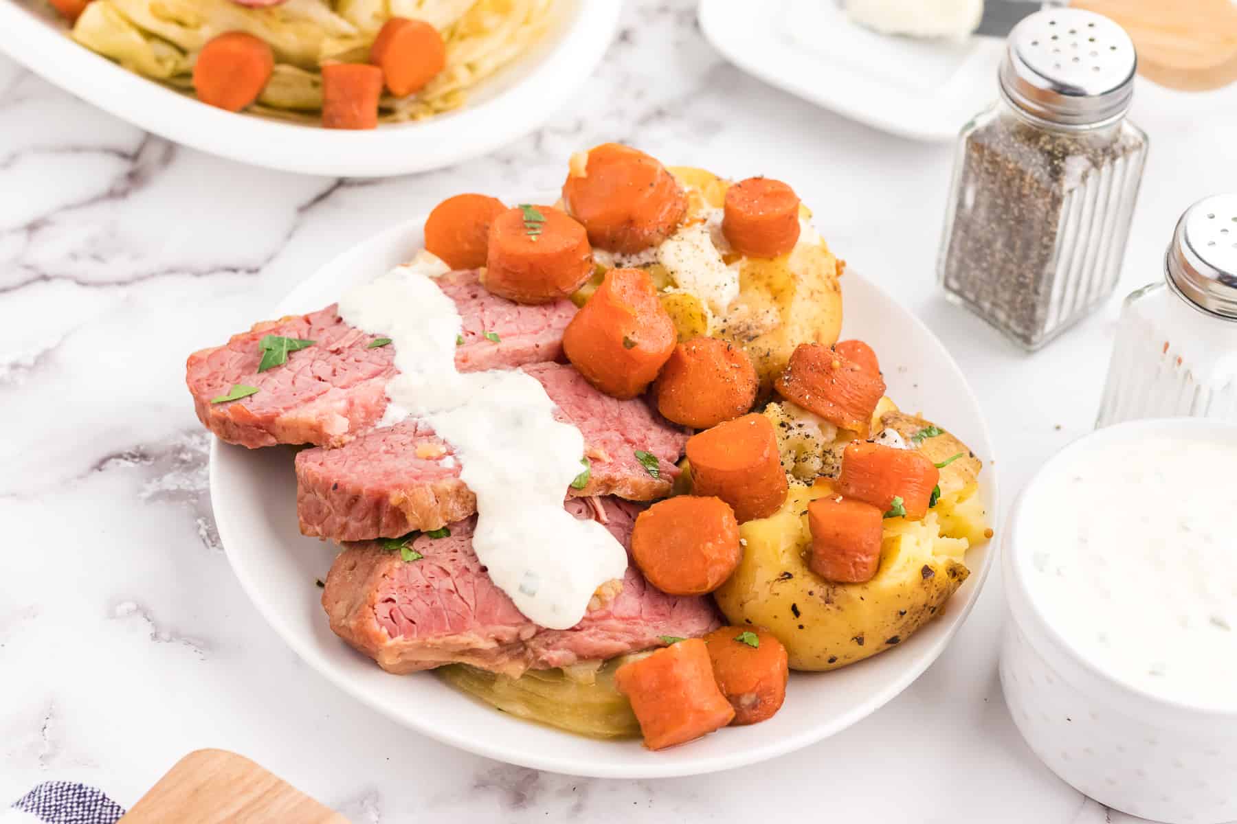 Plated corned beef and cabbage, served with potatoes, carrots and horseradish sauce.