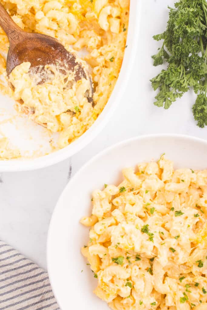 creamy baked mac and cheese recipe getting spooned into a bowl after baking