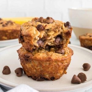 Two baked oatmeal cups on a white plate with one having a bite taken out.