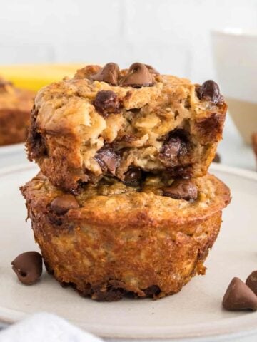 Two baked oatmeal cups on a white plate with one having a bite taken out.
