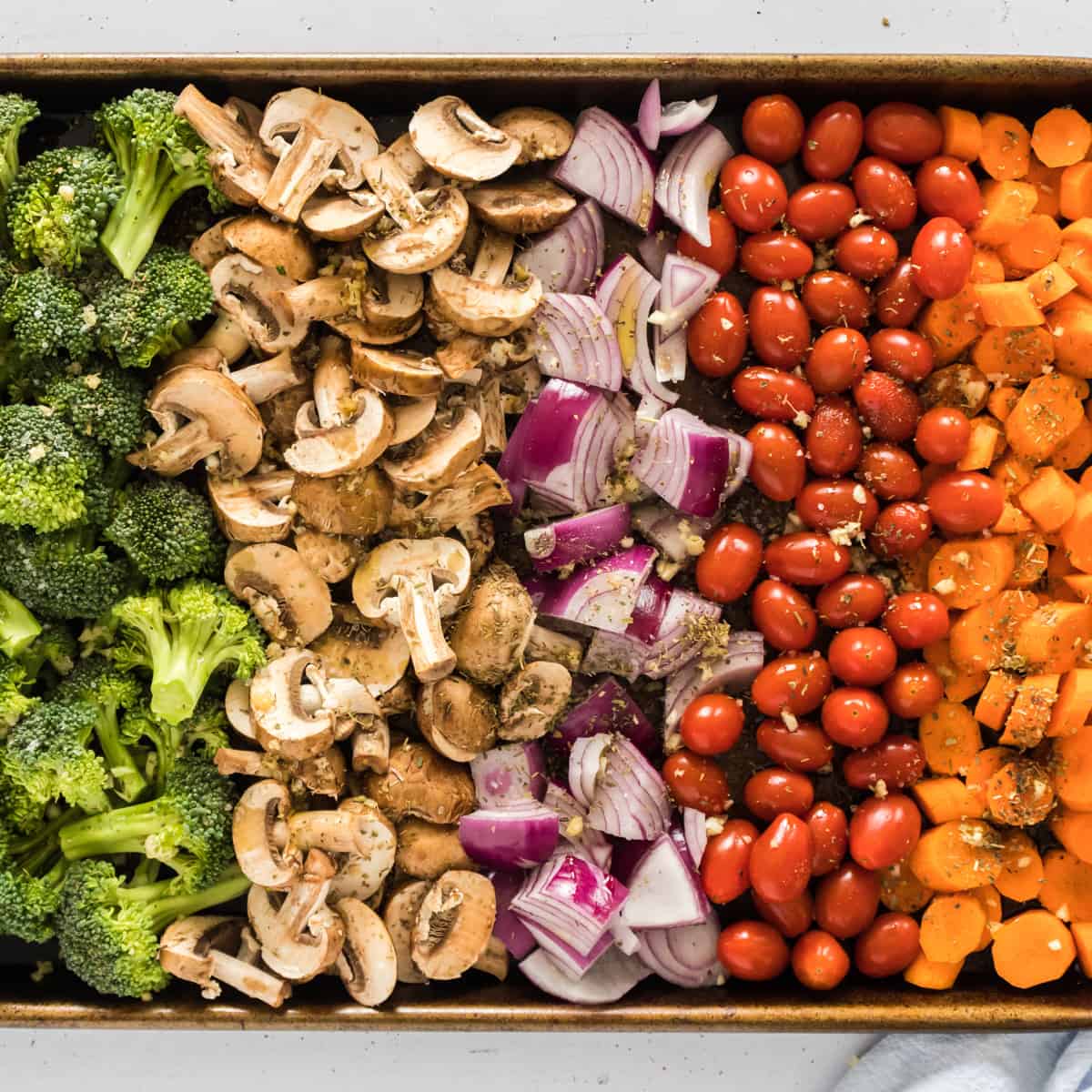 A sheet pan of veggies layered next to eachother.