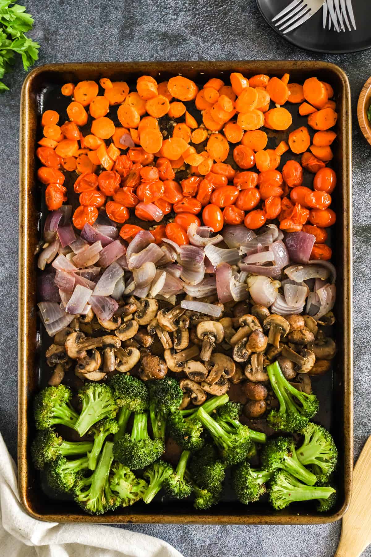A sheet pan of veggies layered next to eachother.