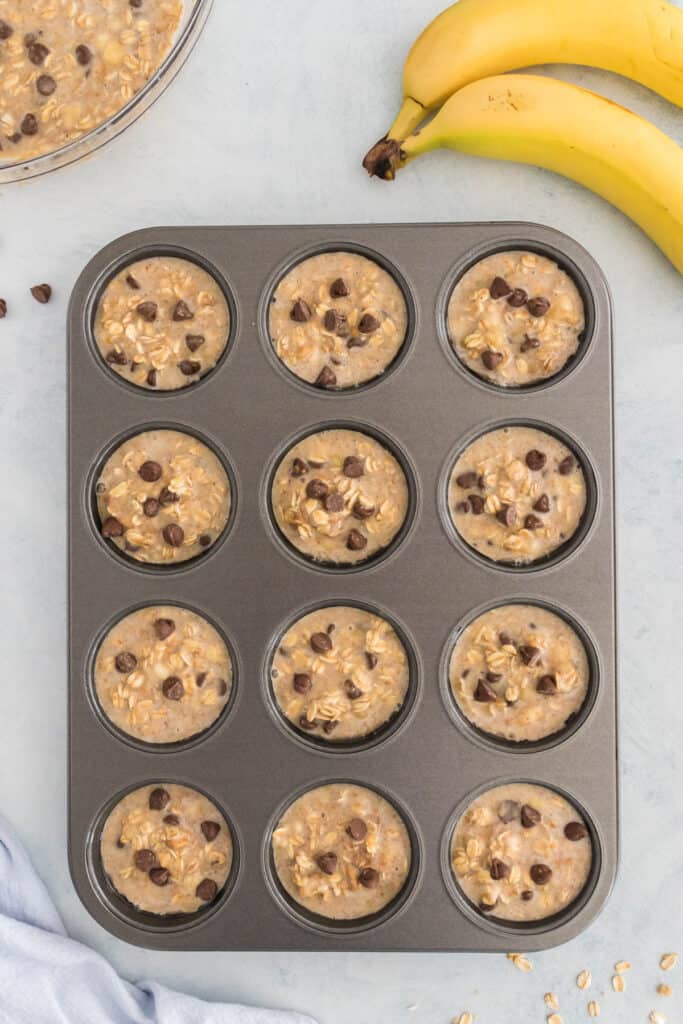 A muffin tin filled with banana oatmeal muffin mix.