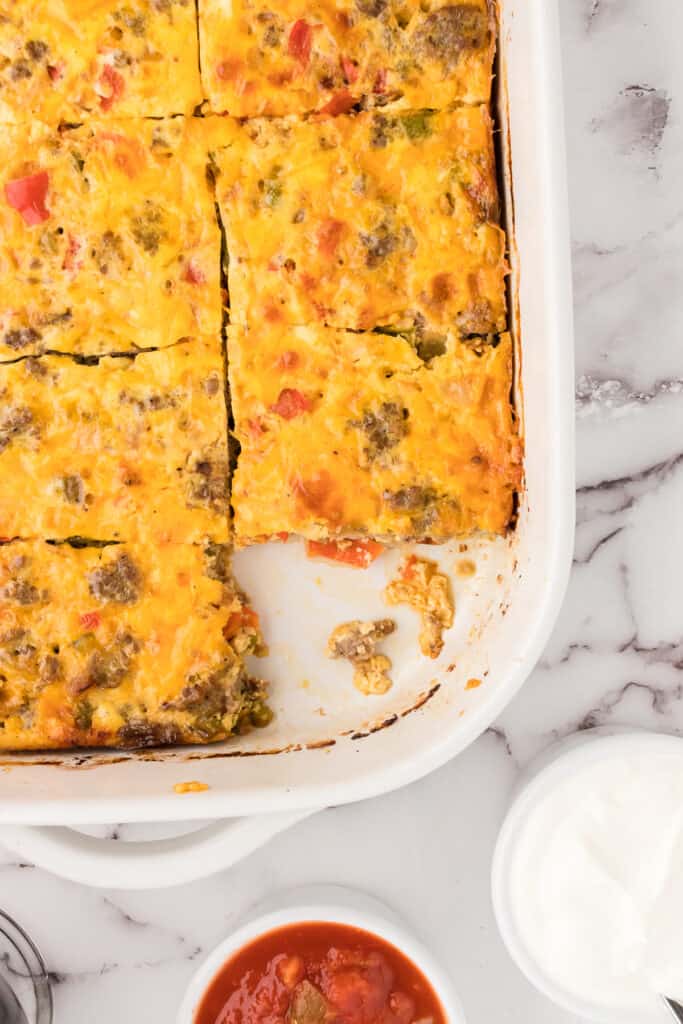 a casserole dish with baked breakfast casserole with a slice taken out.