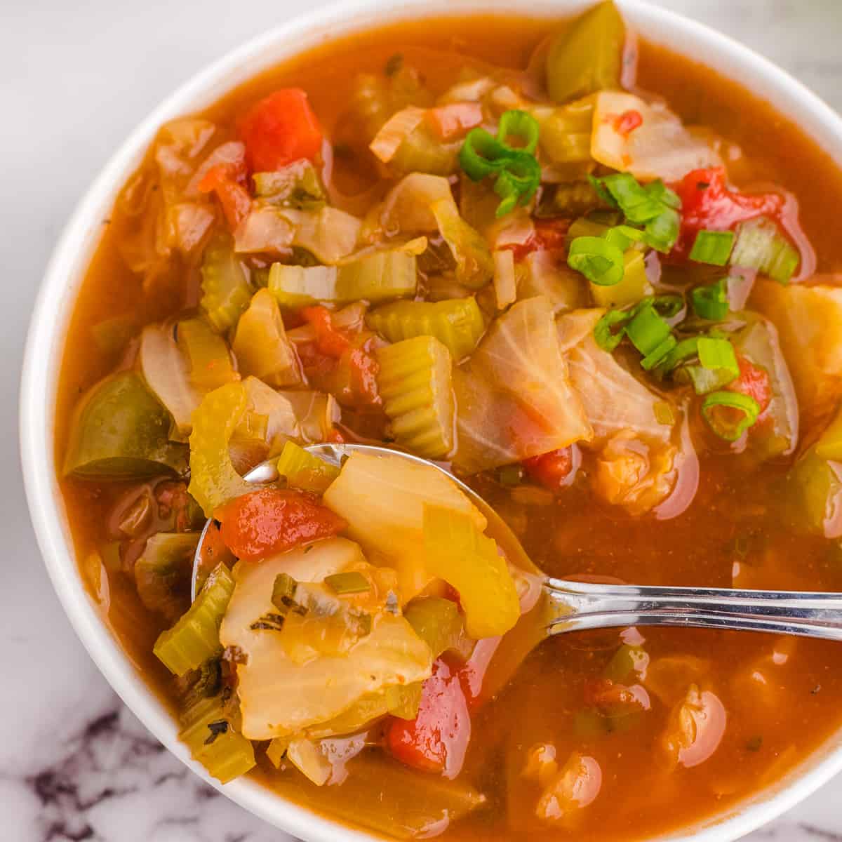 Bowl of detox cabbage soup with a spoon.