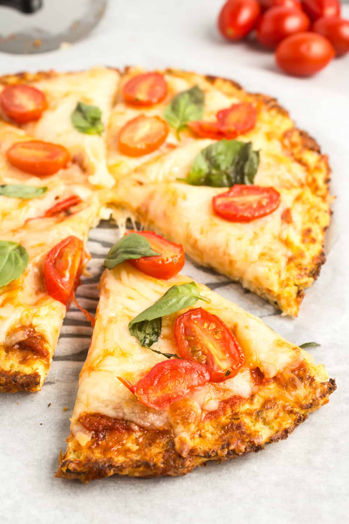 Cooked cauliflower pizza with a slice taken out.