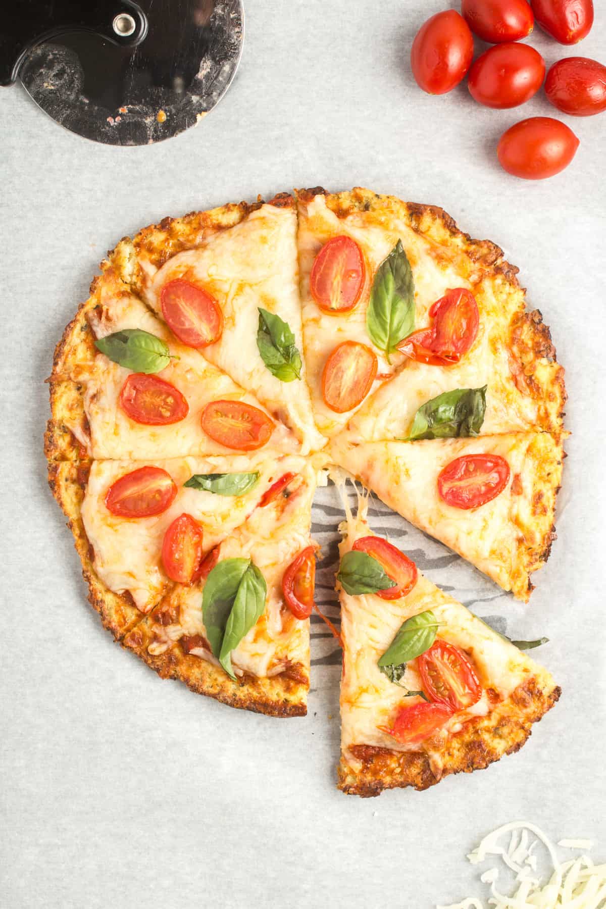 Cooked cauliflower pizza with a slice taken out.