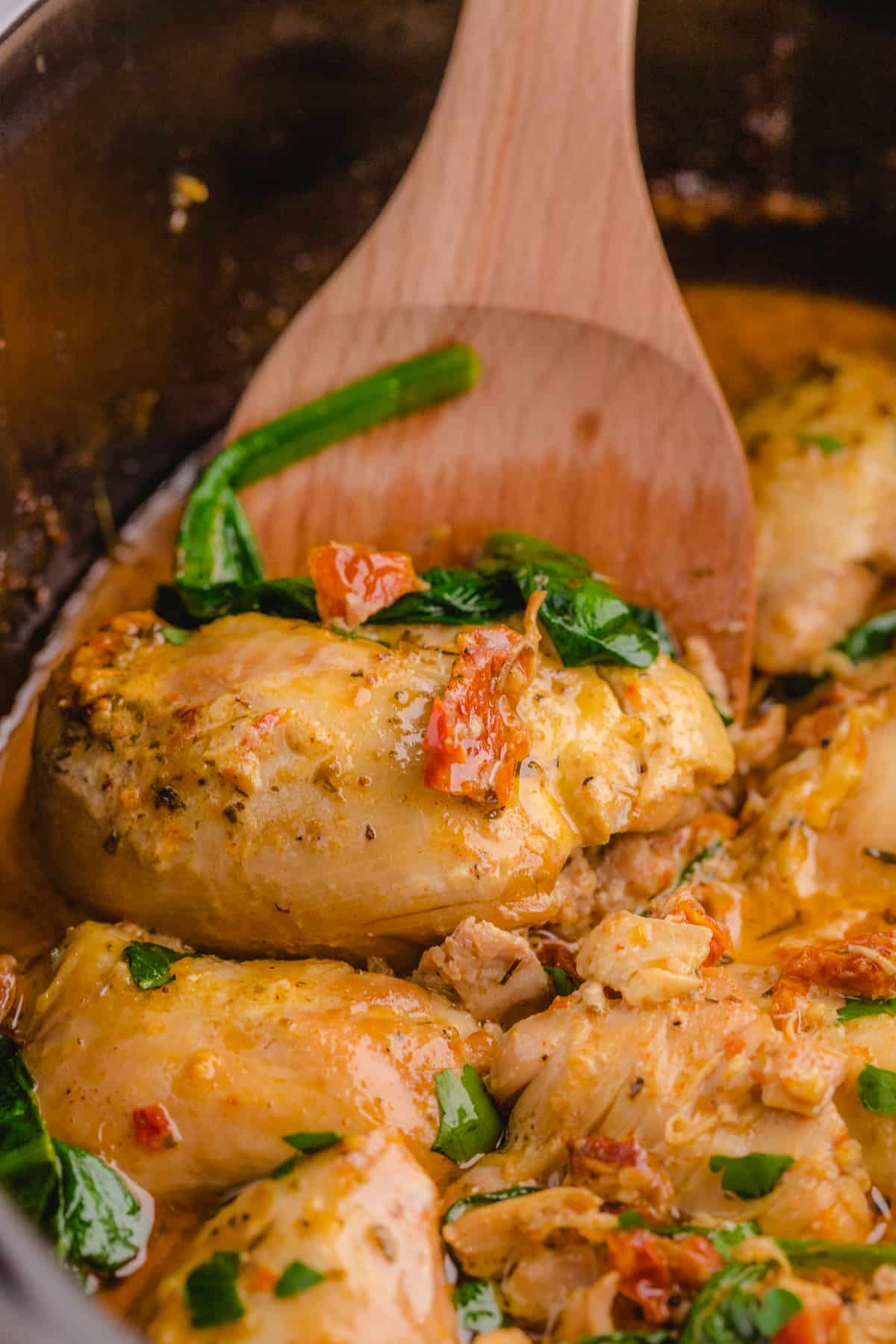 Serving Tuscan chicken with a wooden spoon.