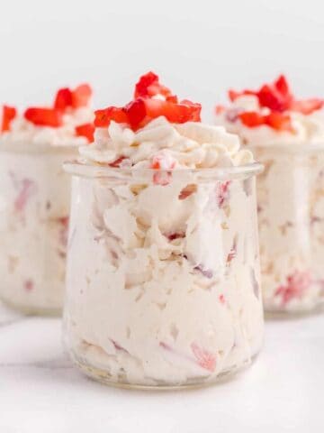 Three jars of keto cheesecake fluff topped with strawberries.