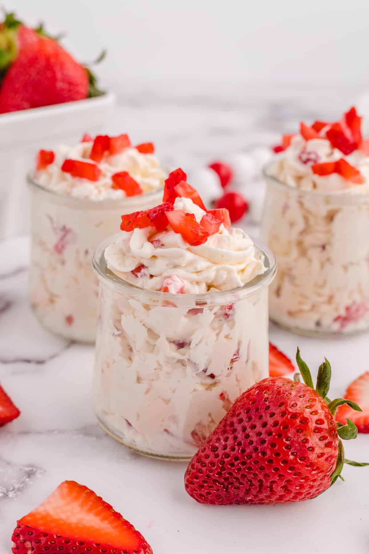 Three jars of keto cheesecake fluff topped with strawberries.