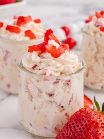 Three jars of keto cheesecake fluff topped with strawberries.