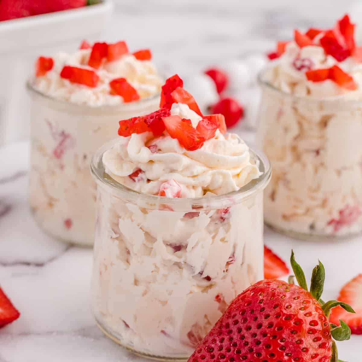 Three jars of keto cheesecake fluff topped with strawberries.