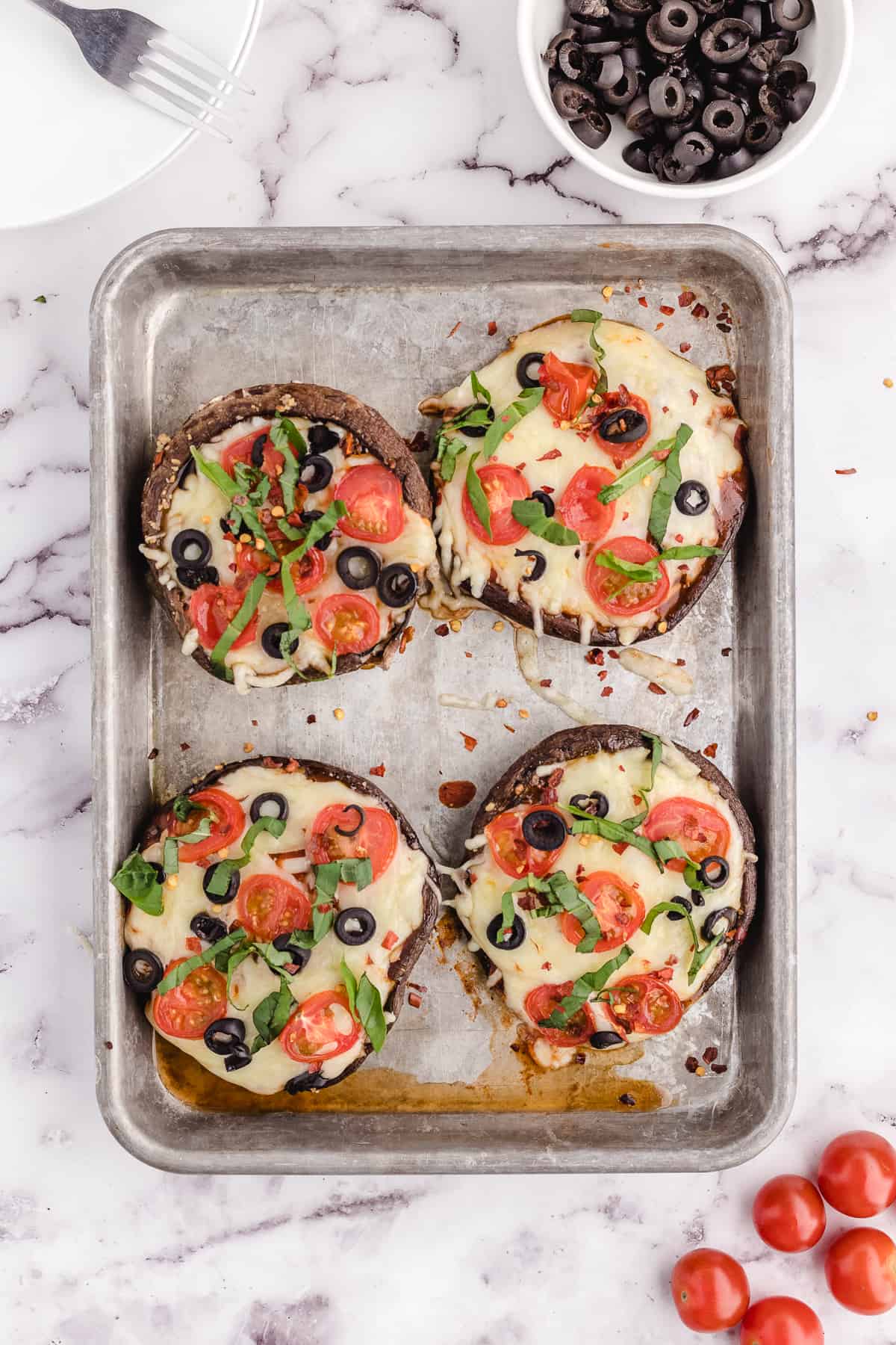 A sheet pan with four baked portobello mushroom caps.