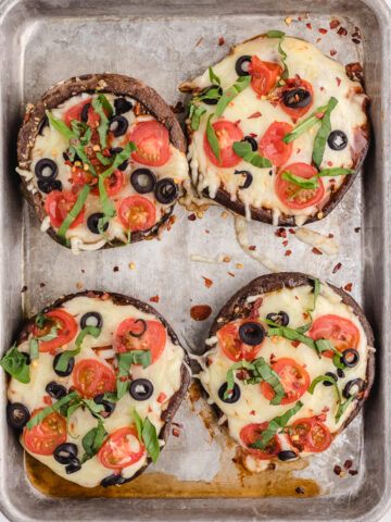 A sheet pan with four baked portobello mushroom caps.