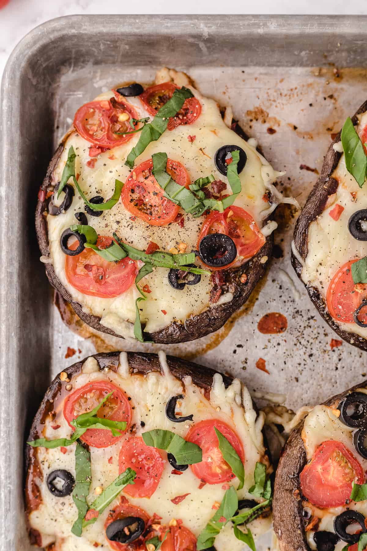 Close up of A sheet pan with four baked portobello mushroom caps.