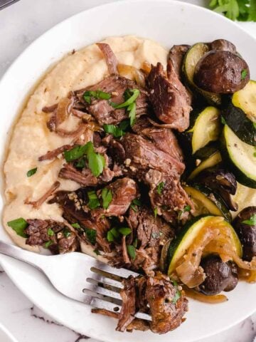 A plate of chuck roast being eaten with a fork.