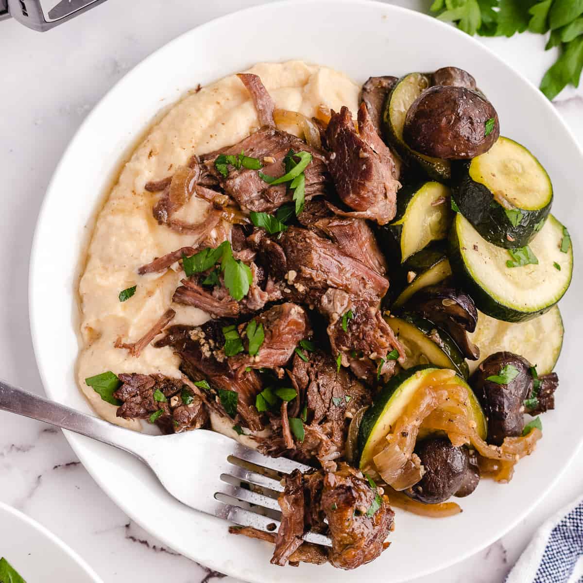 A plate of chuck roast being eaten with a fork.