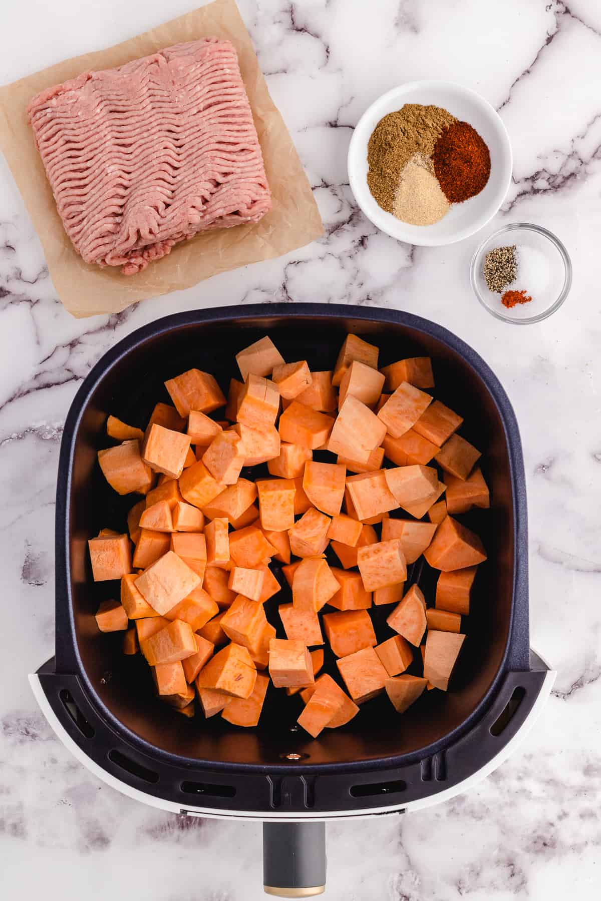 Diced sweet potatoes being cooked in an air fryer.