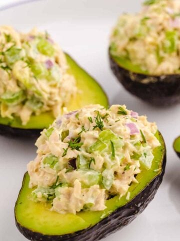 Four avocado halves filled with tuna salad.