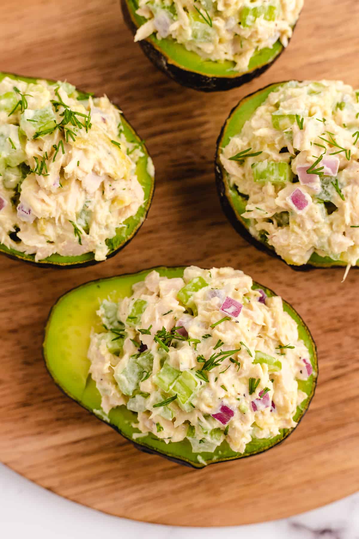 Four avocado halves filled with tuna salad.