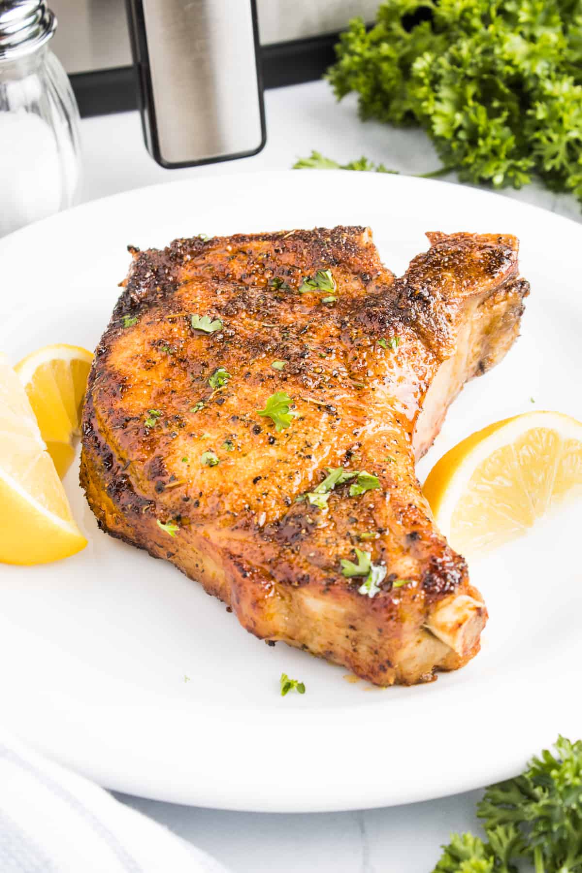 A plated bone in pork chop on a plate.